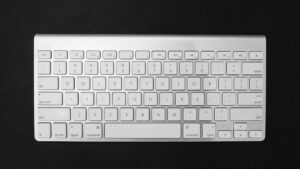 White computer keyboard photographed from above on a dark surface.